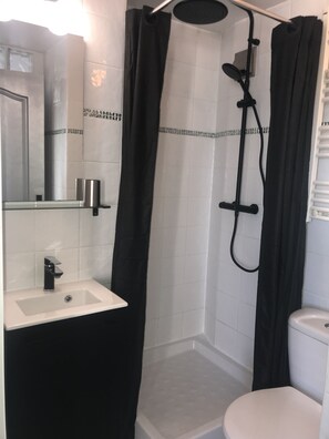 Een bad/douchecombinatie, een haardroger, handdoeken