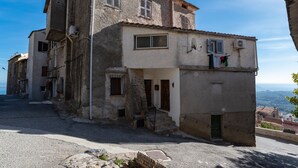 A two-story building with a stone facade, a small porch, and a view of the surrounding area. - Pentone - One Bedroom Apartment, Sleeps 4 (Cervione)