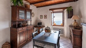 A cozy dining area with a wooden table, chairs, and a cabinet with glass doors. - Pentone - One Bedroom Apartment, Sleeps 4 (Cervione)