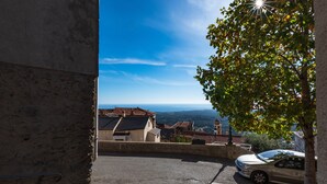 A view from a window overlooking a street with a parked car and buildings with tiled roofs. - Pentone - One Bedroom Apartment, Sleeps 4 (Cervione)