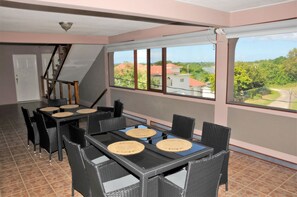 Een eetgedeelte met een tafel voor vier personen, een trap en grote ramen met uitzicht op het omliggende landschap.