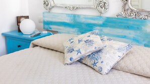 A bed with beige bedding and blue star-patterned pillows, a white globe on a blue nightstand, and a mirror with an ornate frame. - Beb La Bella Annacapri  (Anacapri)