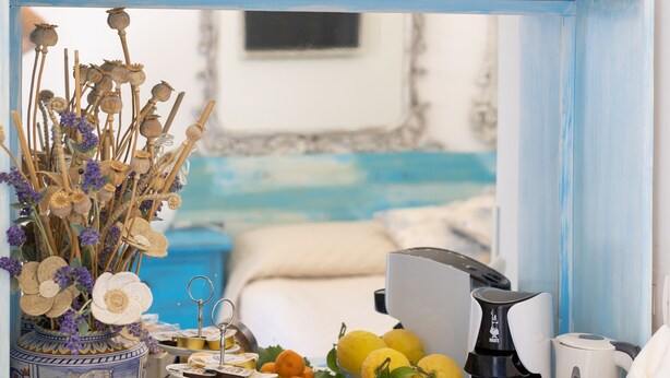 A blue-framed shelf with decorative items, a coffee maker, and a variety of food and drink containers. - Beb La Bella Annacapri  (Anacapri)
