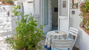 A patio with a table and chairs, a hanging light fixture, a potted plant, and a door leading to an interior space. - Beb La Bella Annacapri  (Anacapri)
