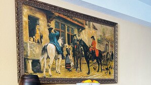 A wooden cabinet with intricate carvings and a painting above it.