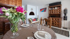 A dining area with a round table set for four, a vase of flowers, and a bookshelf in the background. - Altea Beach Front 'Oden 5' < 4 persons (Altea)