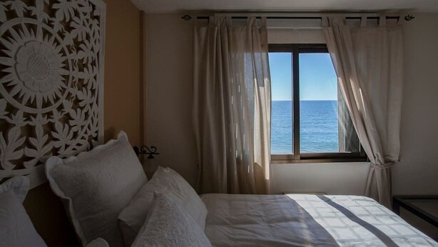 A bedroom with a bed, a decorative wall panel, and a window with curtains.