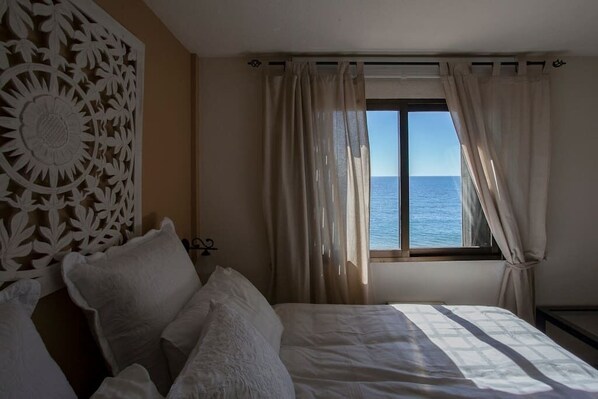 Une chambre à coucher avec un lit, un panneau décoratif au mur et une fenêtre avec des rideaux.