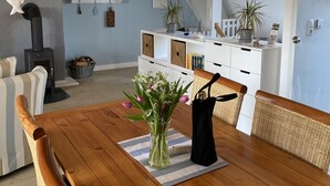Et spiseområde med et træbord, fletstole og en hængende lampe.