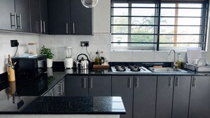 A modern kitchen with black cabinets, a gas stove, a blender, and a window with a view of greenery.