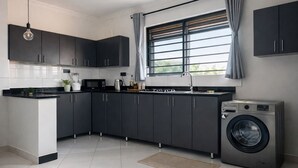 A modern kitchen with dark cabinets, a built-in microwave, a gas stove, and a front-loading washing machine.