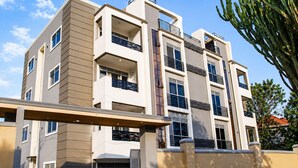 A multi-story building with balconies, a garage, and a clear sky.