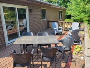 A deck with a table and chairs, a sliding glass door, and a small garden area.