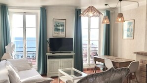 Una habitación con cama, televisor, mesa de comedor y sillas. Cuenta con un balcón con vistas al mar.