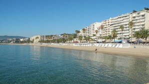 Un hotel frente al mar con varios pisos, una playa de arena y agua cristalina.