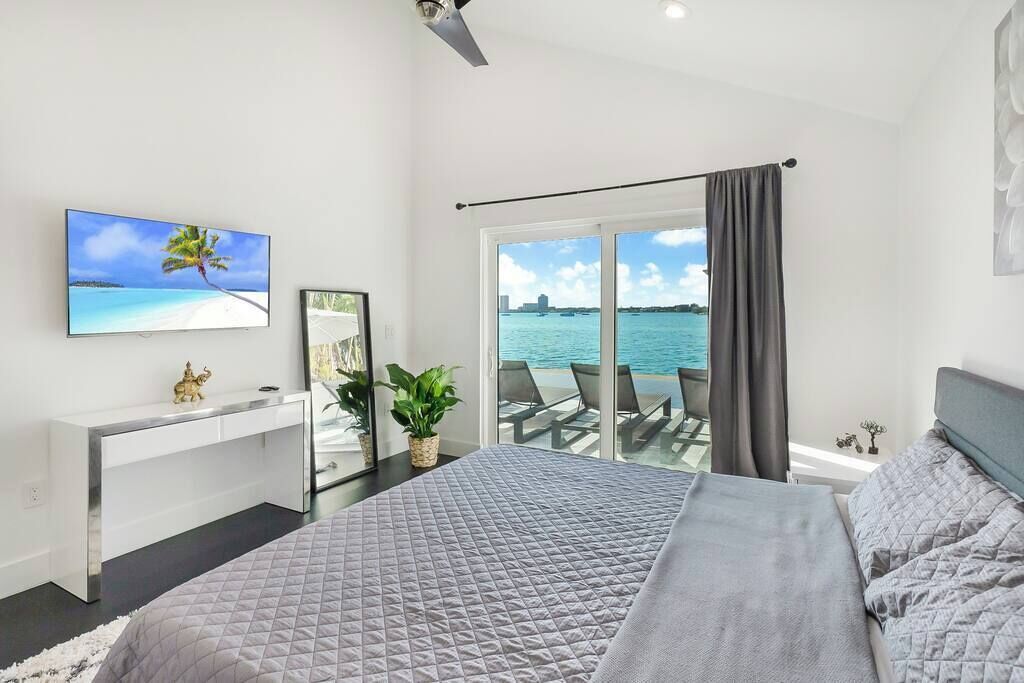 Une chambre avec un lit, un bureau, une télévision, une plante et une vue sur la mer.