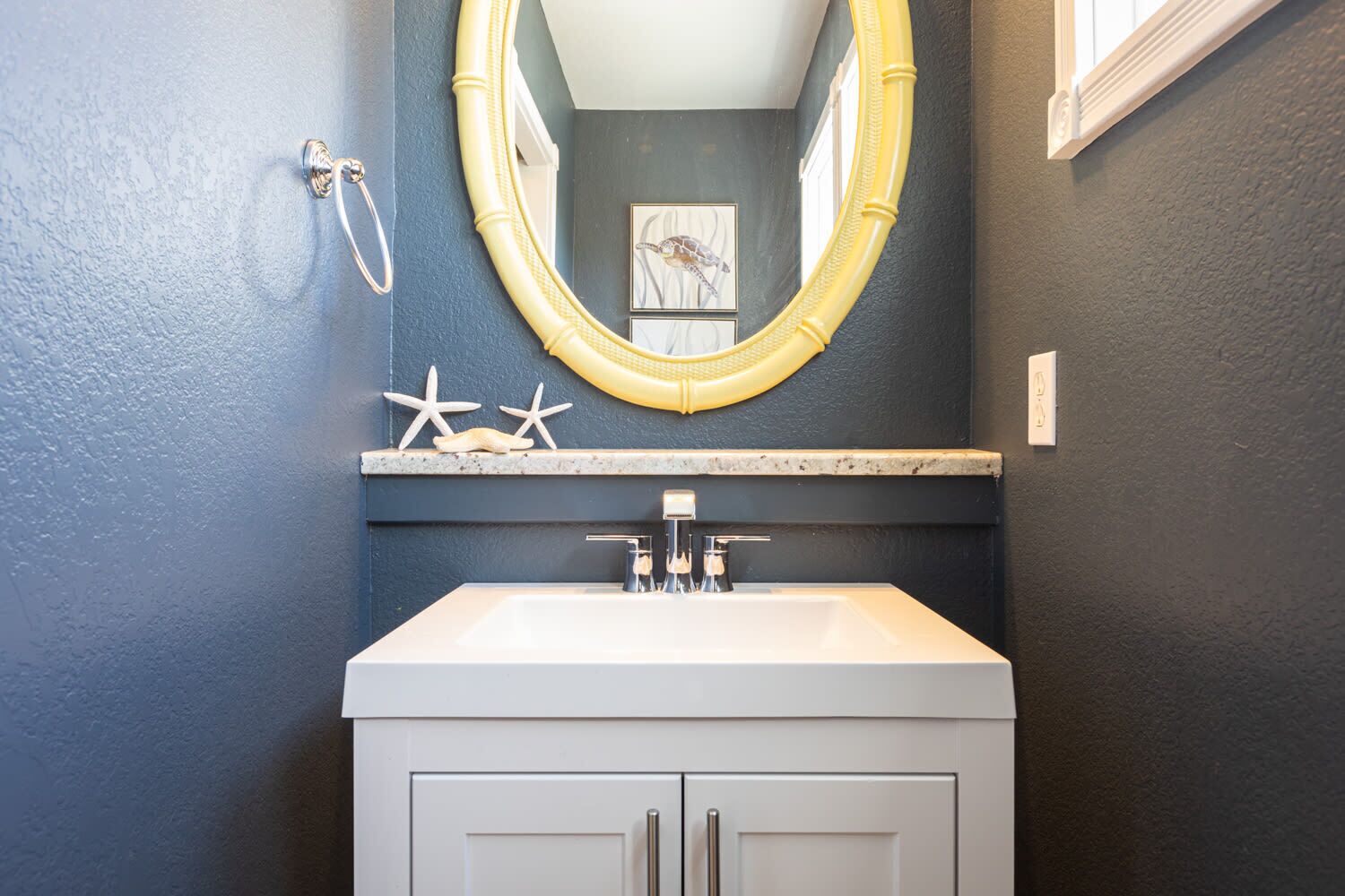 A bathroom with a white vanity, a large mirror with a gold frame, and a wall-mounted towel rack.