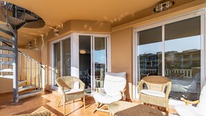 Ein Balkon mit Korbmöbeln, einem weißen Stuhl und einer Wendeltreppe.