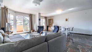 Ein modernes Wohnzimmer mit einer Couch, Sesseln, einem Couchtisch und einem Essbereich mit Stühlen und Tisch.