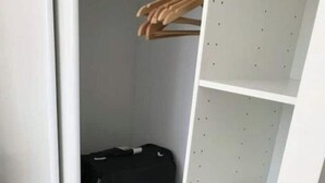 Ein Schrank mit einem schwarzen Koffer und einer weißen Regaleinheit.