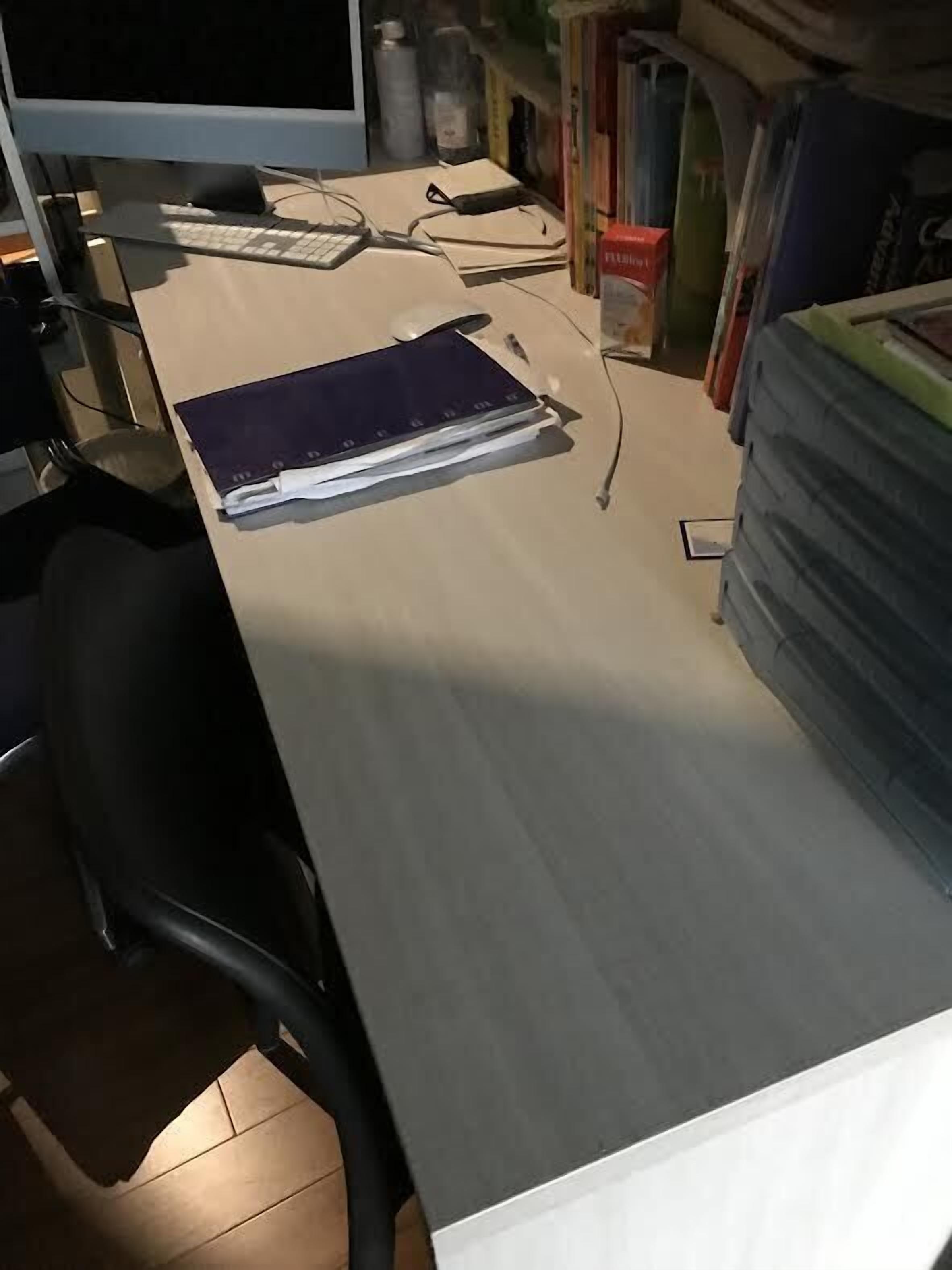 Un bureau avec un écran d’ordinateur, un clavier, une souris, un carnet et une pile de livres.