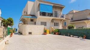 A two-story building with a balcony, potted plants, and a clear blue sky. - apuliablue (Bari)