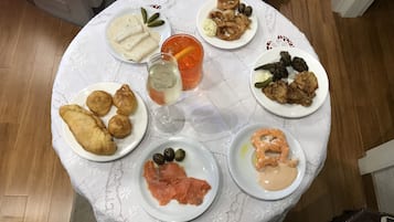 A round dining table with various dishes including seafood, bread, and a glass of white wine.
