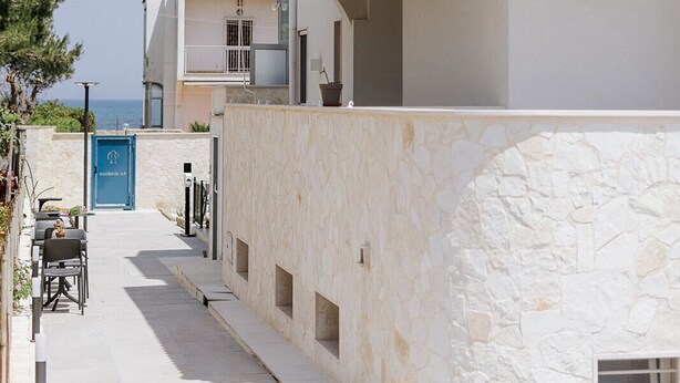 A coastal building with a tiled roof, a blue awning, and a stone wall. - apuliablue (Bari)