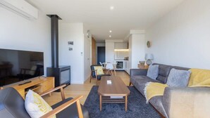 Uma sala de estar moderna com sofá, poltrona, TV e lareira.