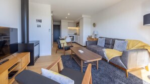 Uma sala de estar moderna com sofá, mesa de centro e painel para TV.