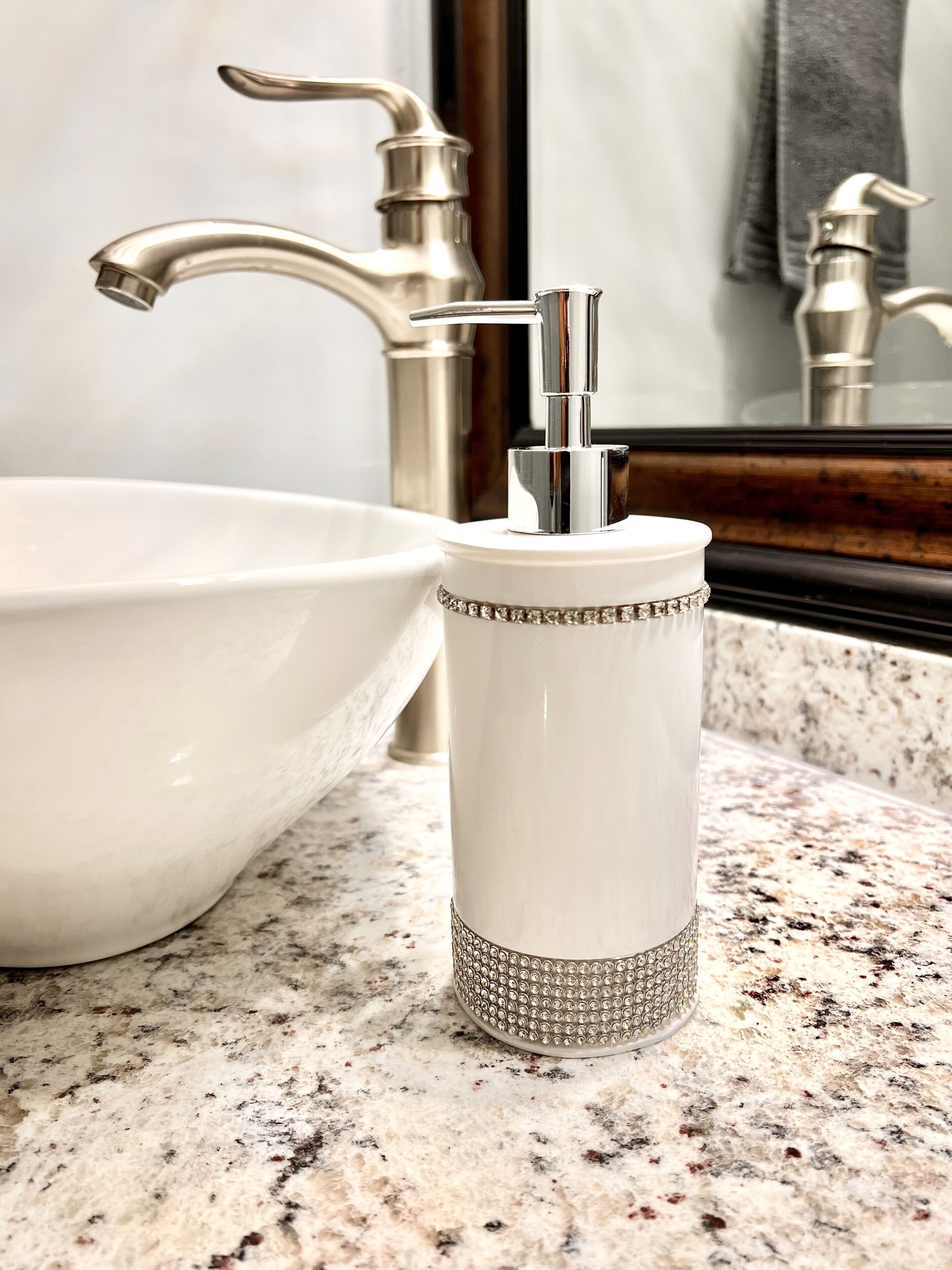 A bathroom sink with a modern faucet and a decorative, textured soap dispenser.