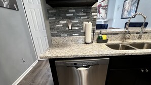 A kitchen with a granite countertop, stainless steel dishwasher, and a black cabinet above the sink. - 2bd 2.5 ba Sleeps 6 Luxury Townhome, Jacksonville NC. Close To Camp Lejeune (Jacksonville)