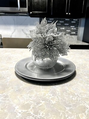 Uma tigela decorativa prateada sobre uma bancada de mármore em uma cozinha.
