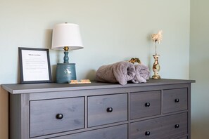 A grey dresser with a framed welcome sign, a lamp, and decorative items including a dried flower arrangement. - Charming Beachside Escape Patio Parking (Indialantic)