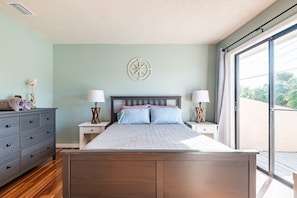 Een slaapkamer met een bed, twee nachtkastjes, een dressoir en een groot raam.