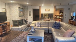 A living room with a fireplace, a sectional sofa, a coffee table, and a patterned rug. - Beautiful waterfront home on Mickey Lake, channeling to 2800 acre Long Lake. AC  (Traverse City)