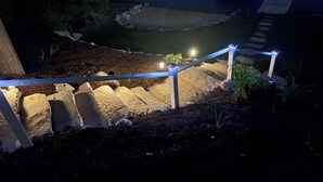 A nighttime outdoor area with a stone pathway, a metal railing, and small lights along the path. - Beautiful waterfront home on Mickey Lake, channeling to 2800 acre Long Lake. AC  (Traverse City)