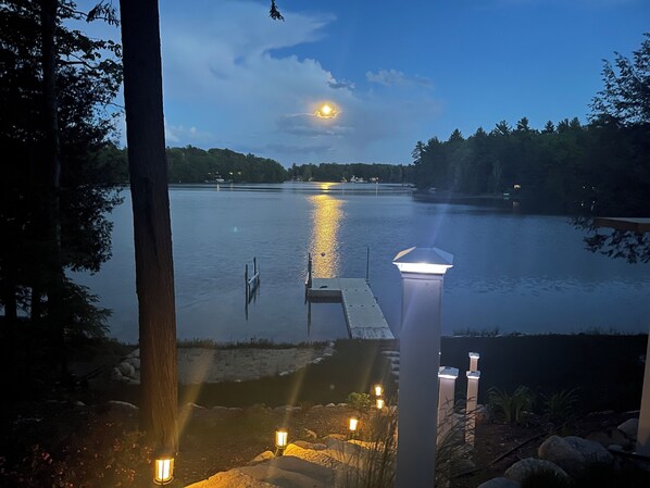 A lakeside view with a dock, stone pathway, and outdoor lighting.