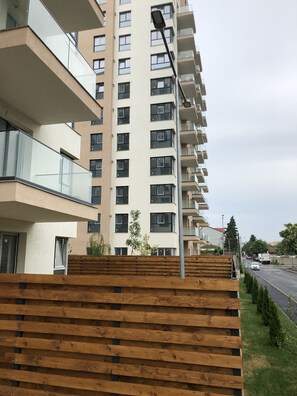 A multi-story residential building with balconies, a street view, and a wooden fence. - 4 Room Penthouse Terrace W18-W19 (Bucharest)