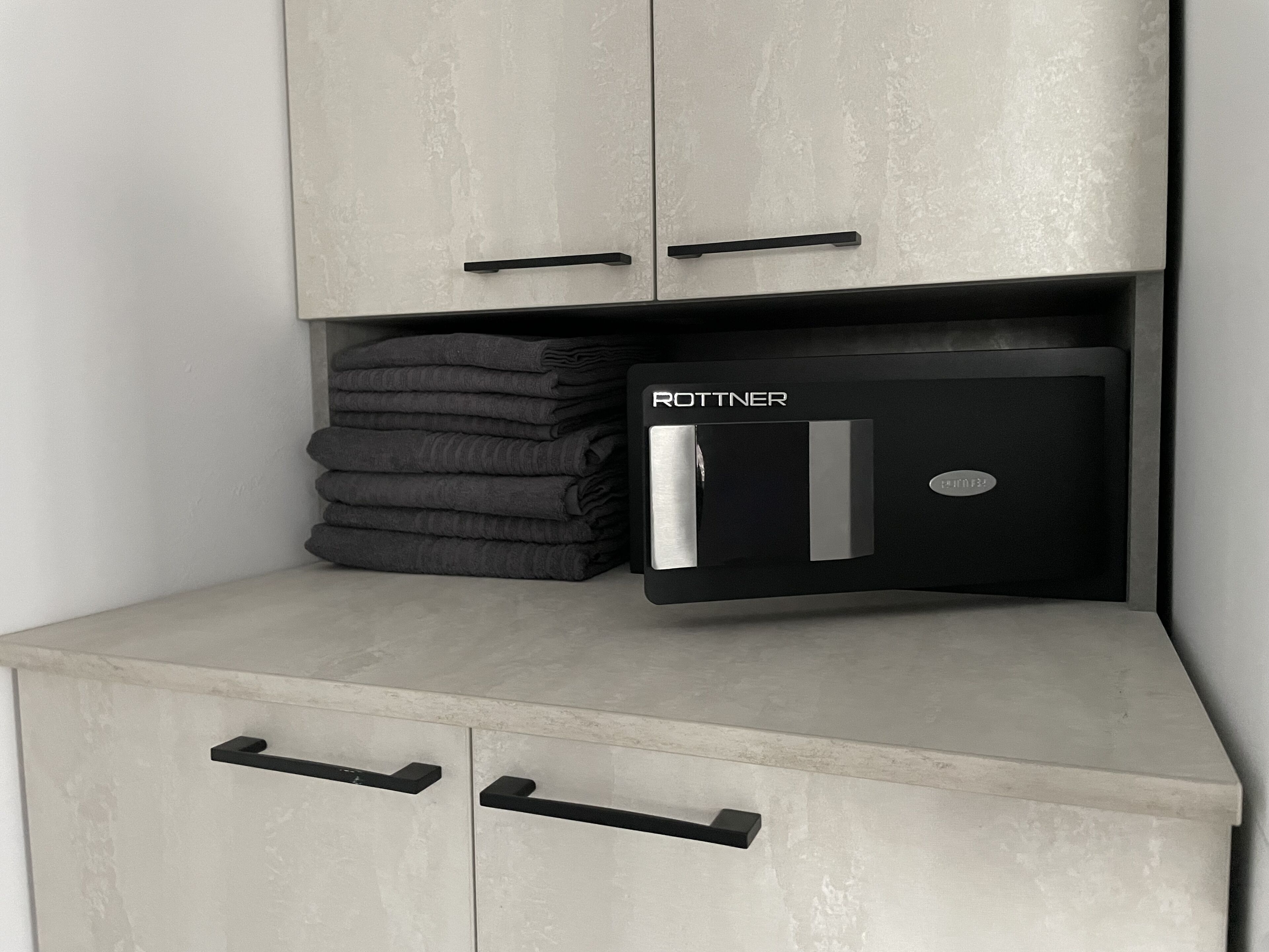 A storage unit with two drawers and a compartment containing folded towels.