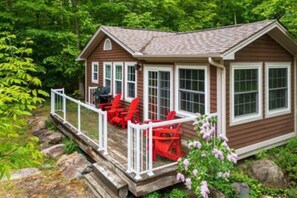 Cozy cabin with a front porch and lush surroundings.