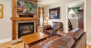 Cozy living room with a fireplace, comfortable seating area, and a view of the outside.