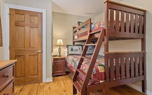 Cozy bedroom with a wooden bunk bed, nightstand, and dresser.