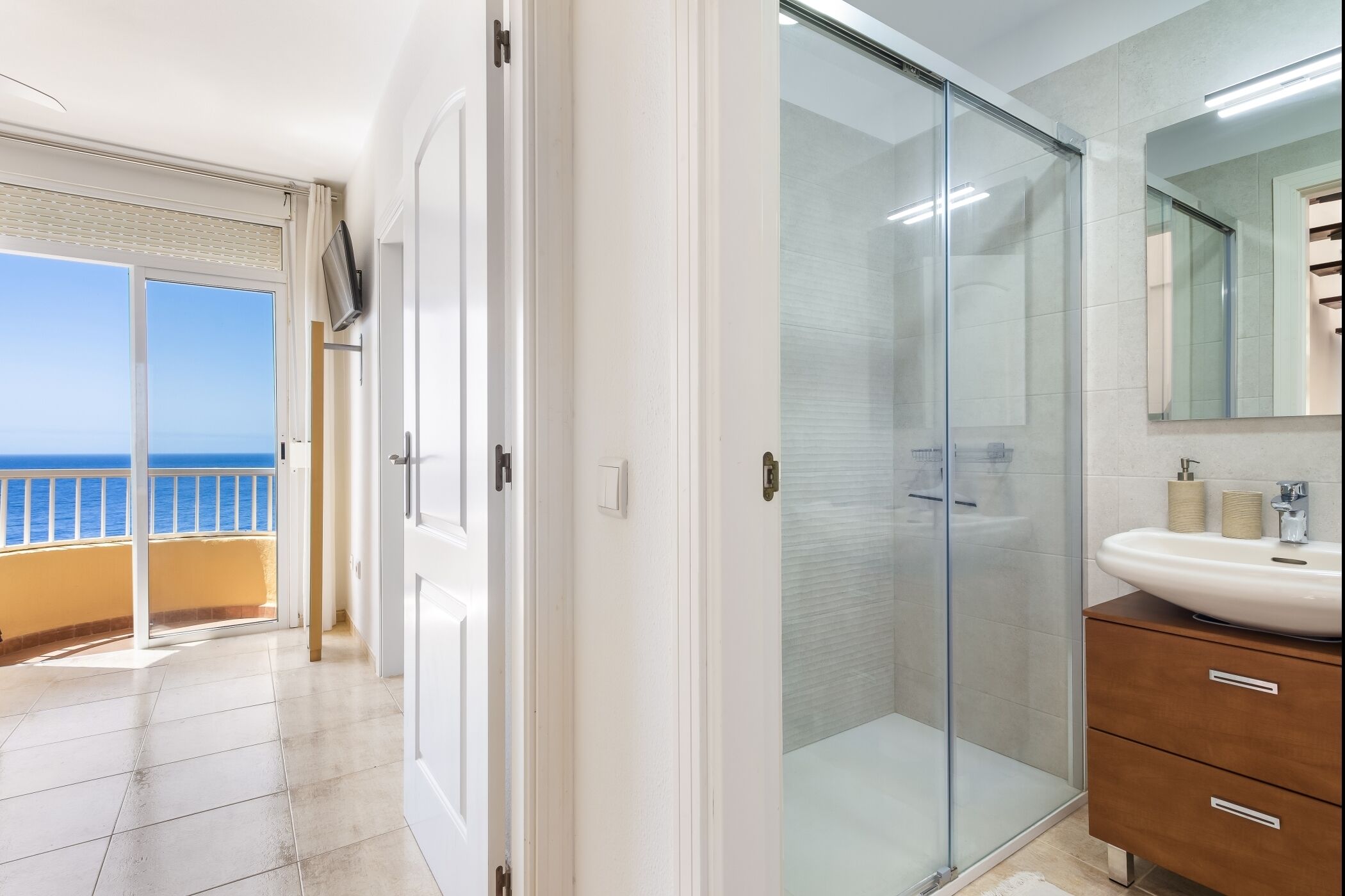 Ein modernes Badezimmer mit Duschkabine aus Glas, einem großen Spiegel und einem weißen Waschbecken.