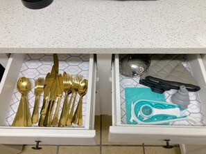 Un cajón de cocina con utensilios y un colador.