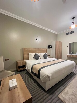 Ein Hotelzimmer mit einem großen Bett, Nachttischen, einem Holznachttisch, einem Holzbüro, einem Spiegel und einer Deckenleuchte.
