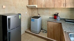 Cocina compacta con refrigerador, lavadora pequeña y pileta.