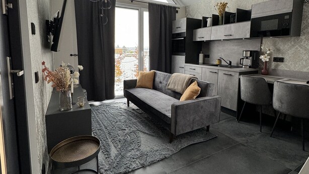 Una cocina moderna con un sofá gris y una zona de comedor.