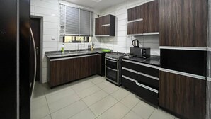 Een moderne keuken met donkerhouten kastjes, een roestvrijstalen koelkast, een gasfornuis en een zwarte magnetron.