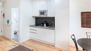 Een moderne keuken met witte kasten, een ingebouwde magnetron en een koffiezetapparaat.